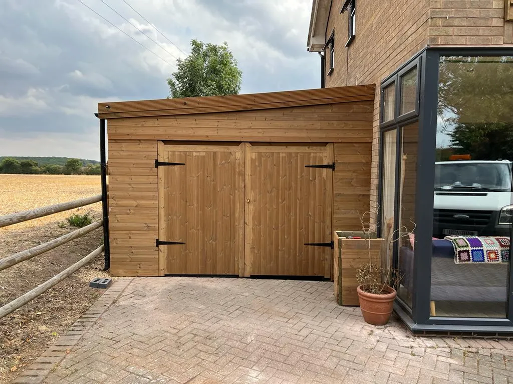 A large wooden garage next to a brick driveway.